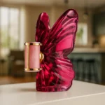 Frasco do perfume La Bomba Carolina Herrera em formato de borboleta rosa com detalhes dourados, exibido em ambiente sofisticado, representando luxo, feminilidade e ousadia.