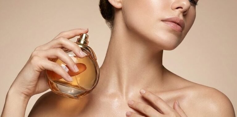 Mulher de pele iluminada aplicando perfume no pescoço, ilustrando a busca por fragrâncias de alta fixação.